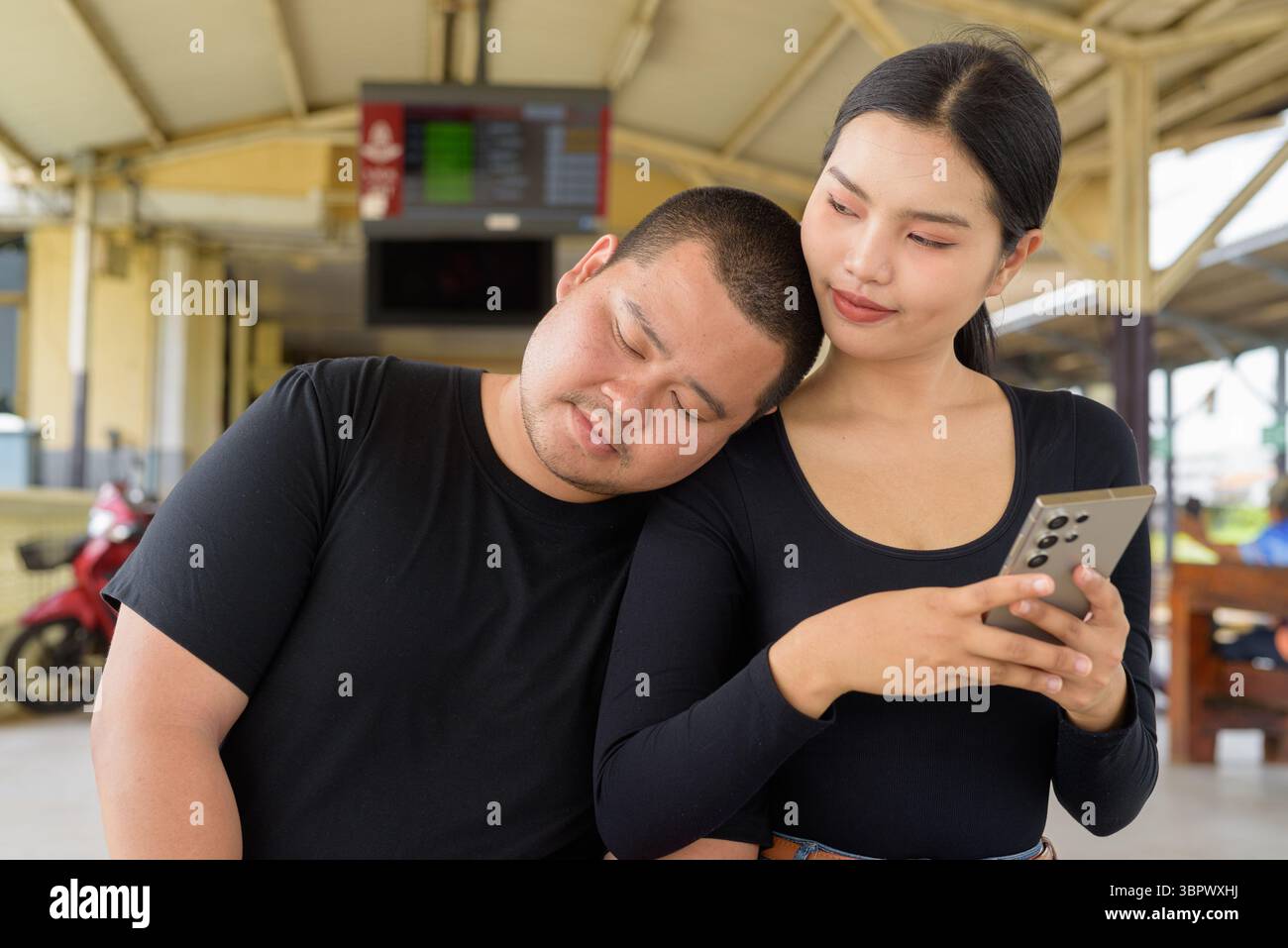 Giovane coppia asiatica in stazione ferroviaria insieme Foto Stock