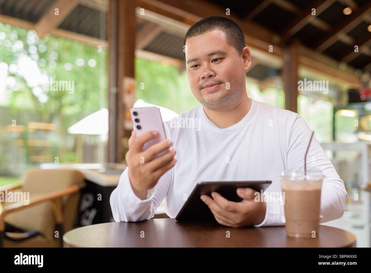 Giovane asiatico più grande uomo felice seduto in un bar ristorante Foto Stock