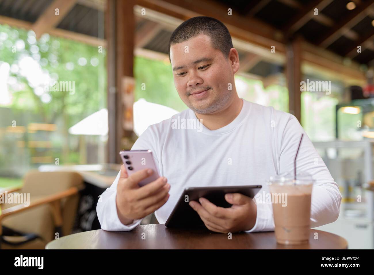 Giovane asiatico più grande uomo felice seduto in un bar ristorante Foto Stock