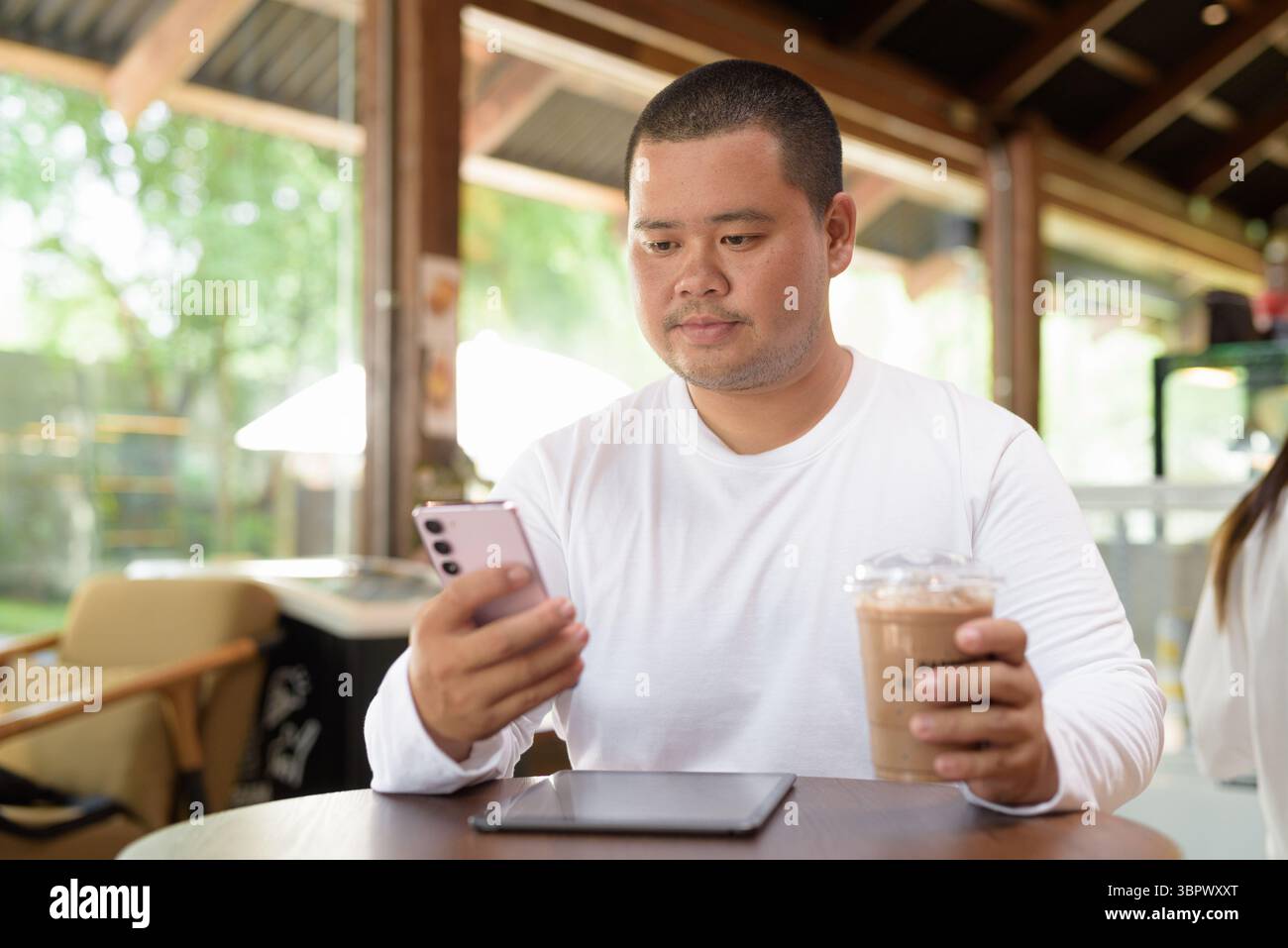 Giovane asiatico più grande uomo felice seduto in un bar ristorante Foto Stock