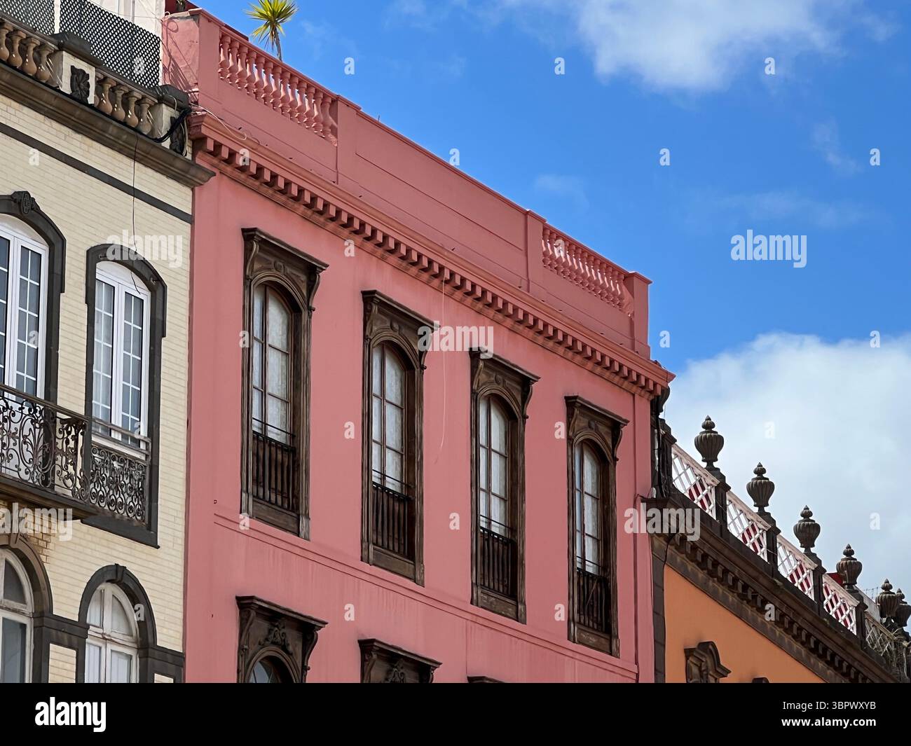Las Palmas, Isole Canarie, Spagna - marzo 13, 2022. Uno splendido edificio rosa con intricati dettagli architettonici si erge su un cielo blu luminoso. Foto Stock
