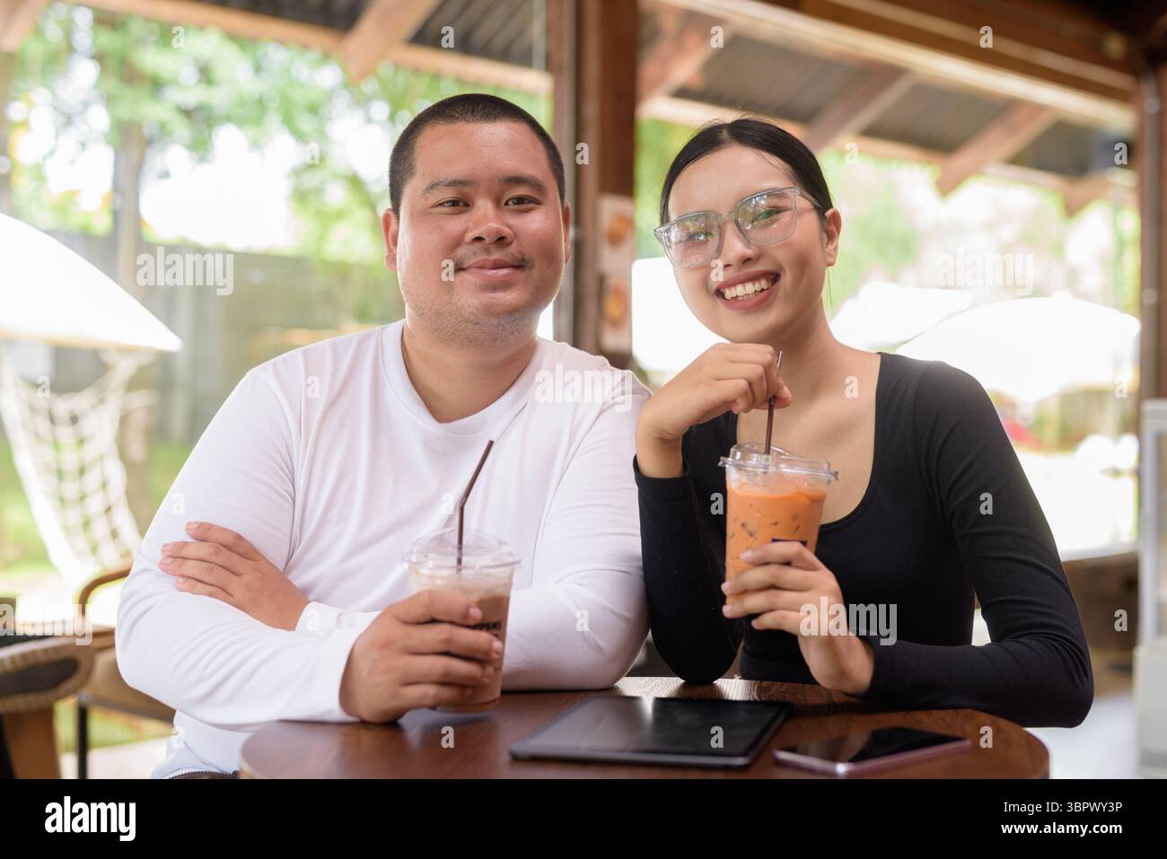 Felice giovane coppia asiatica seduta nel bar Foto Stock