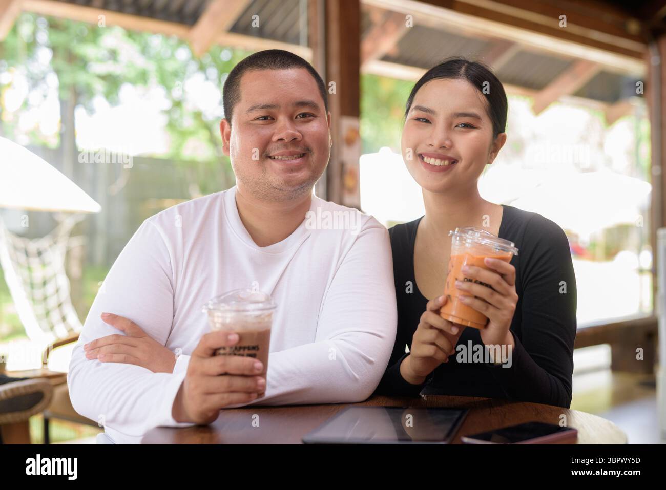 Felice giovane coppia asiatica seduta nel bar Foto Stock