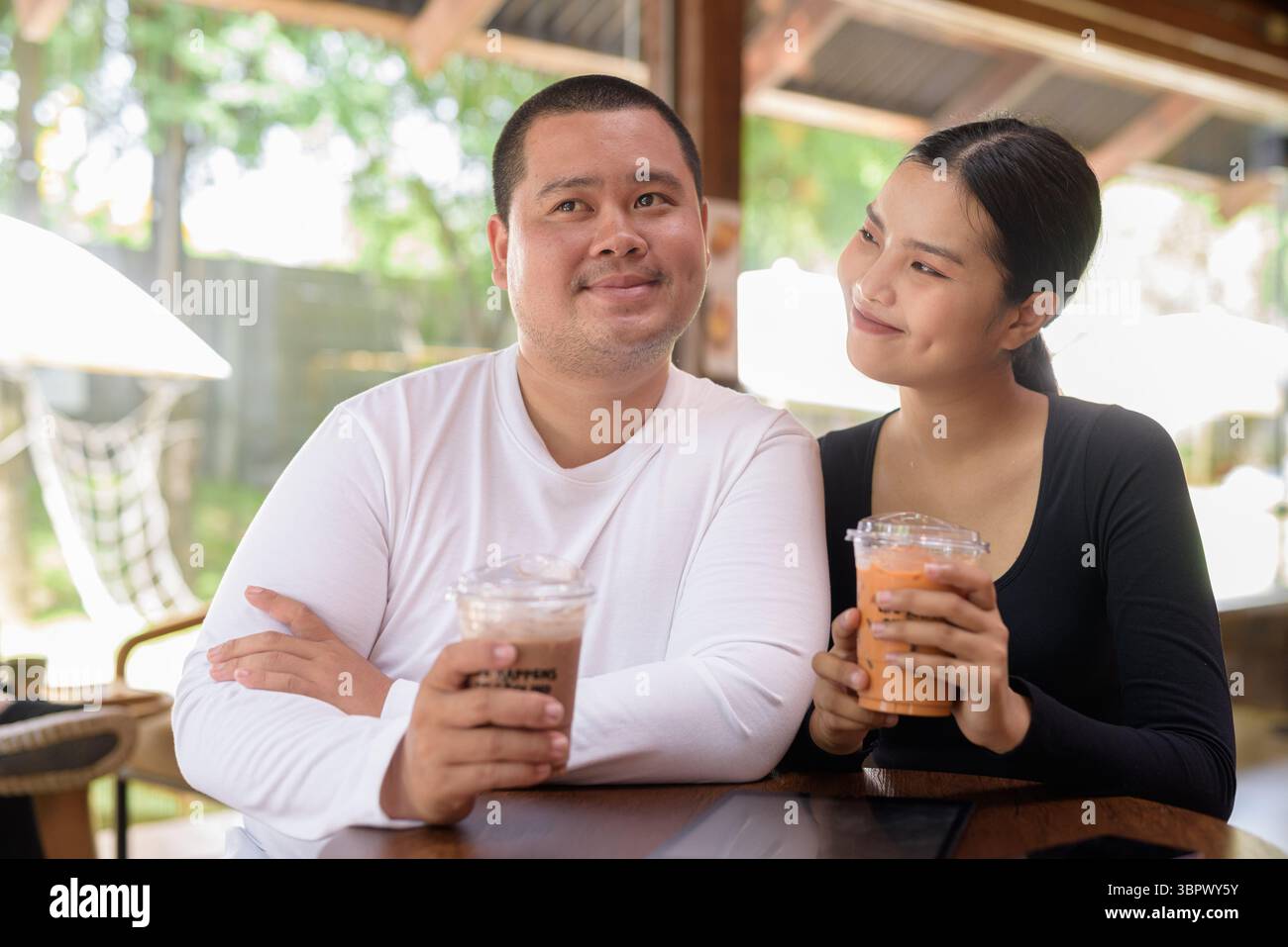 Felice giovane coppia asiatica seduta nel bar Foto Stock