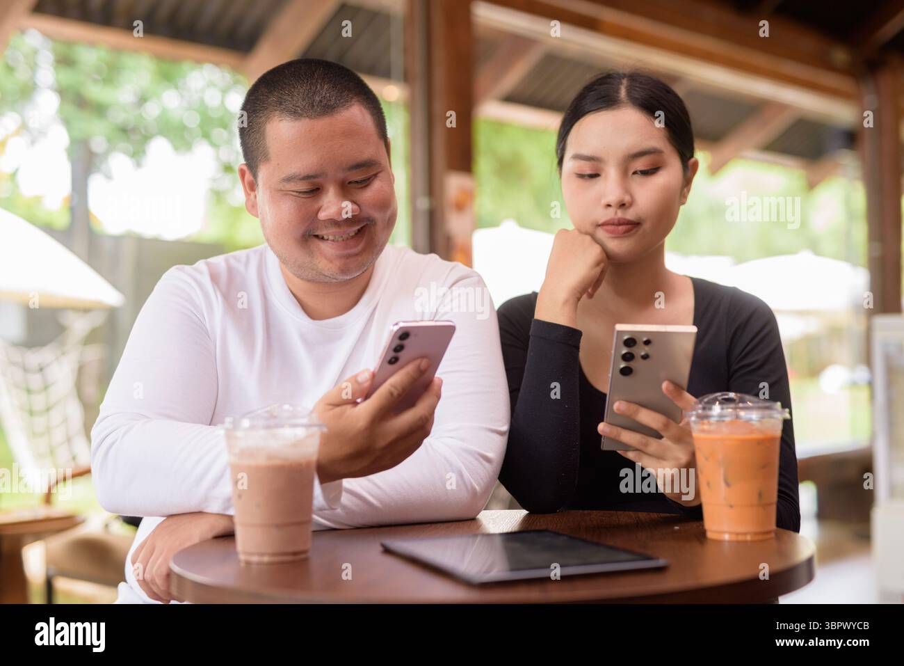 Felice giovane coppia asiatica seduta nel bar Foto Stock