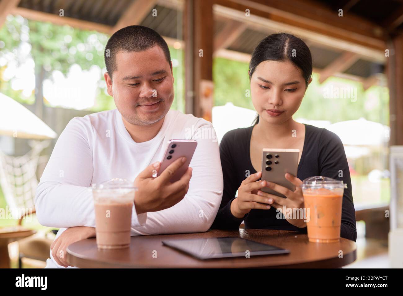 Felice giovane coppia asiatica seduta nel bar Foto Stock