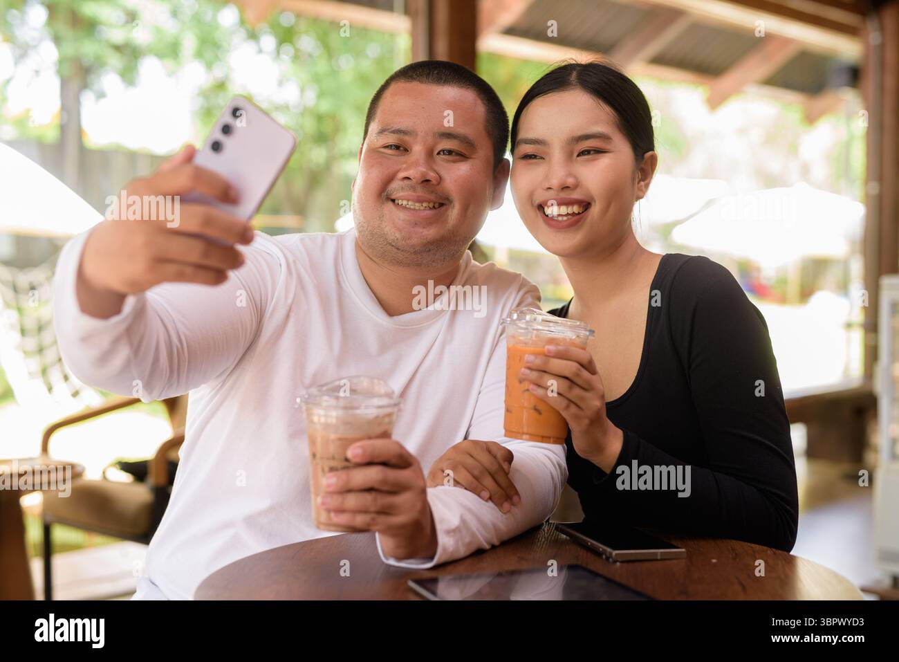 Felice giovane coppia asiatica seduta nel bar Foto Stock
