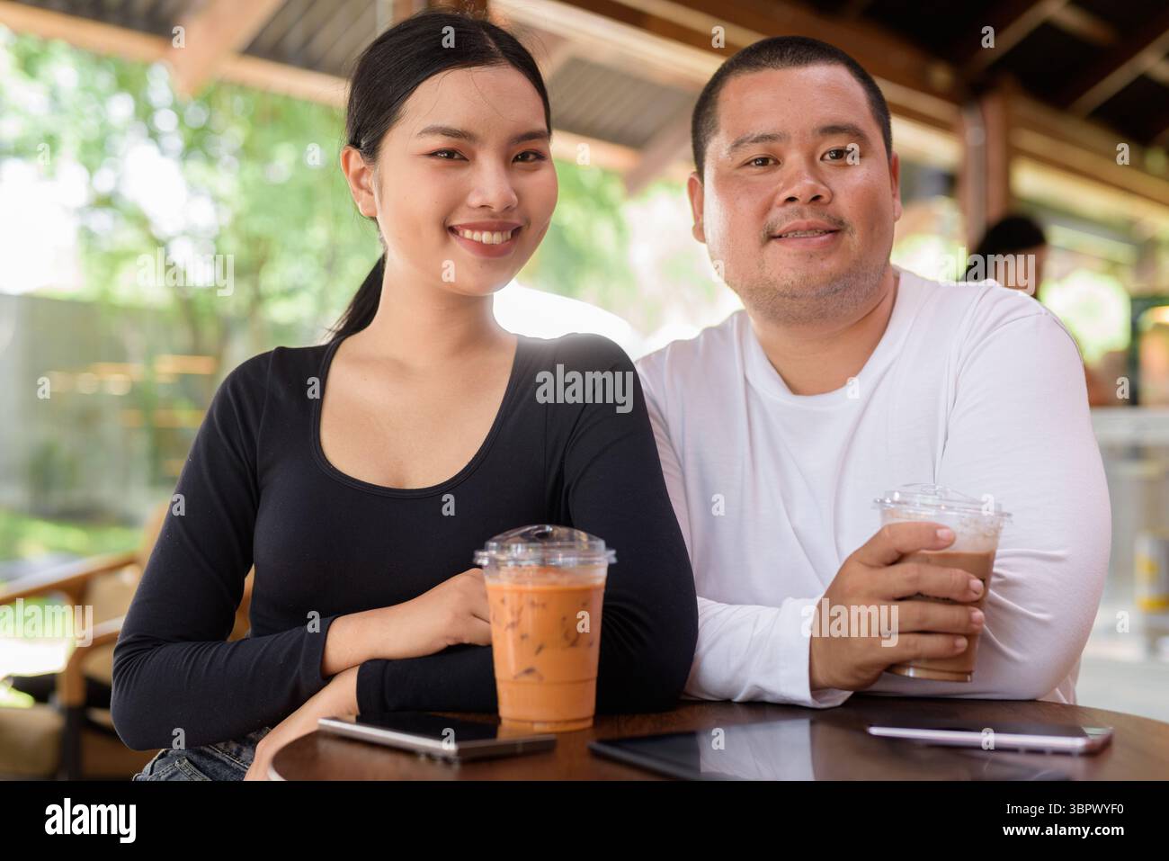 Felice giovane coppia asiatica seduta nel bar Foto Stock