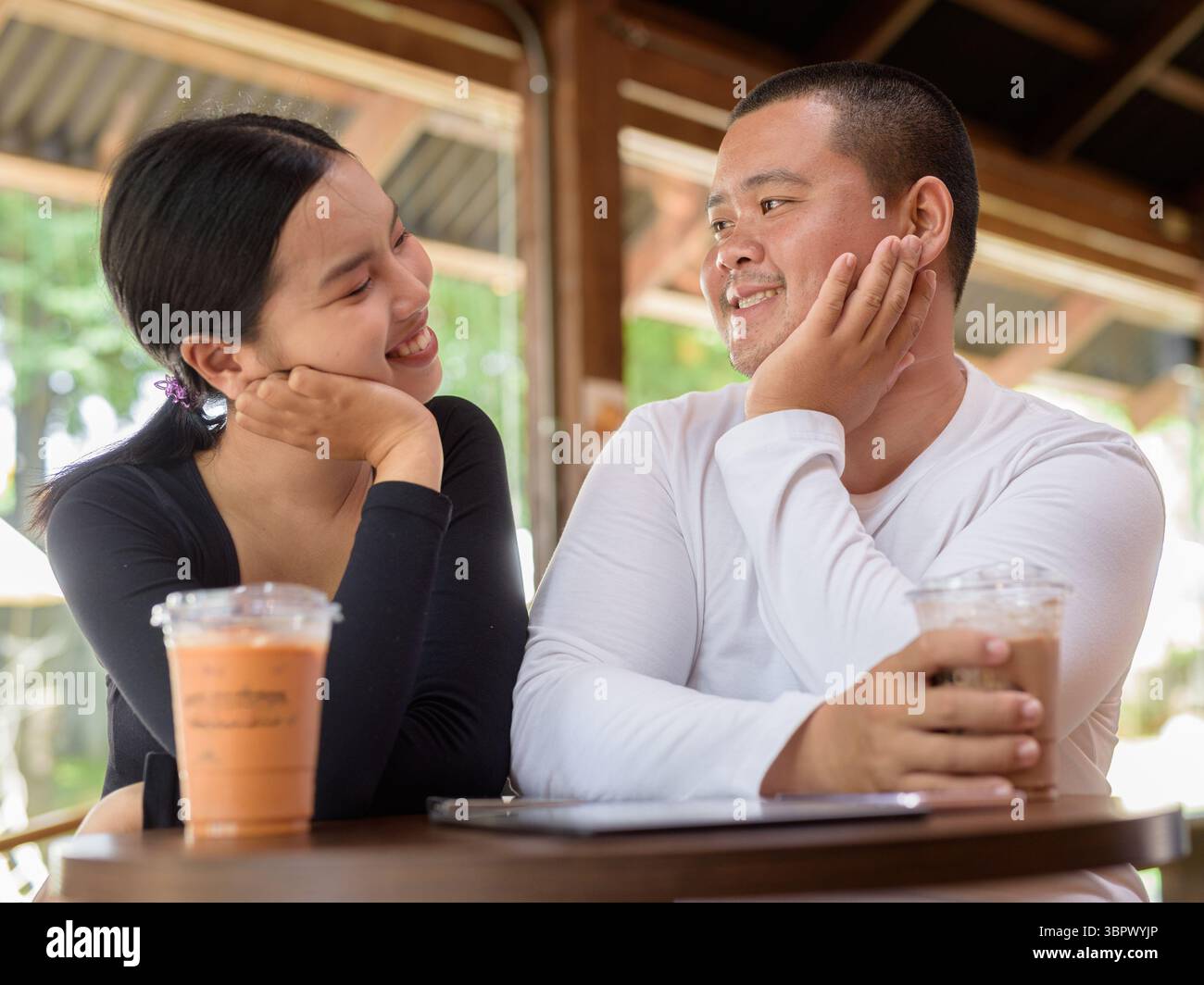 Felice giovane coppia asiatica seduta nel bar Foto Stock