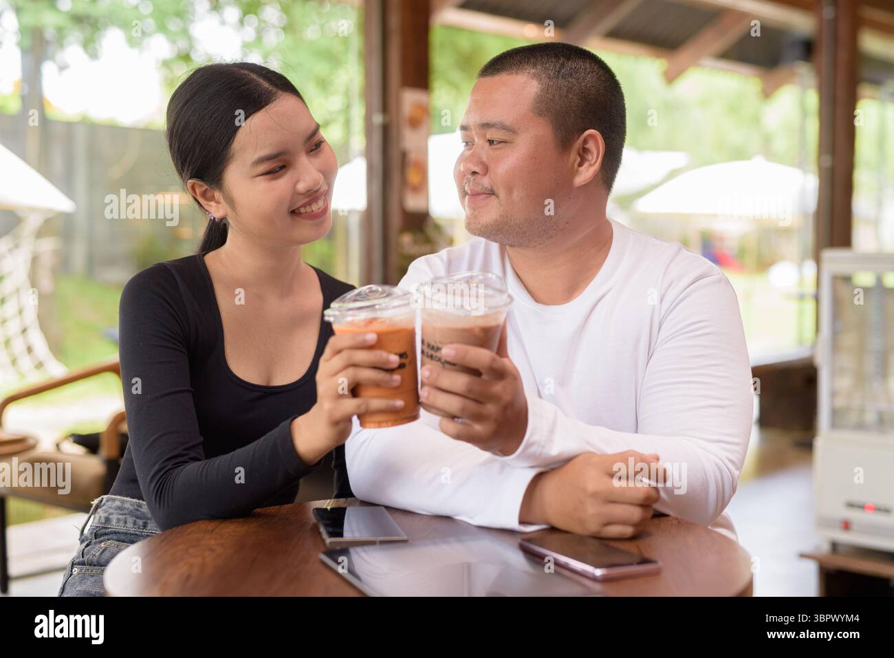 Felice giovane coppia asiatica seduta nel bar Foto Stock