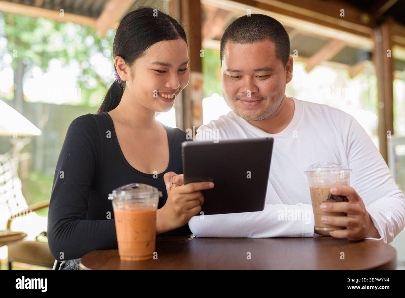 Felice giovane coppia asiatica seduta nel bar Foto Stock
