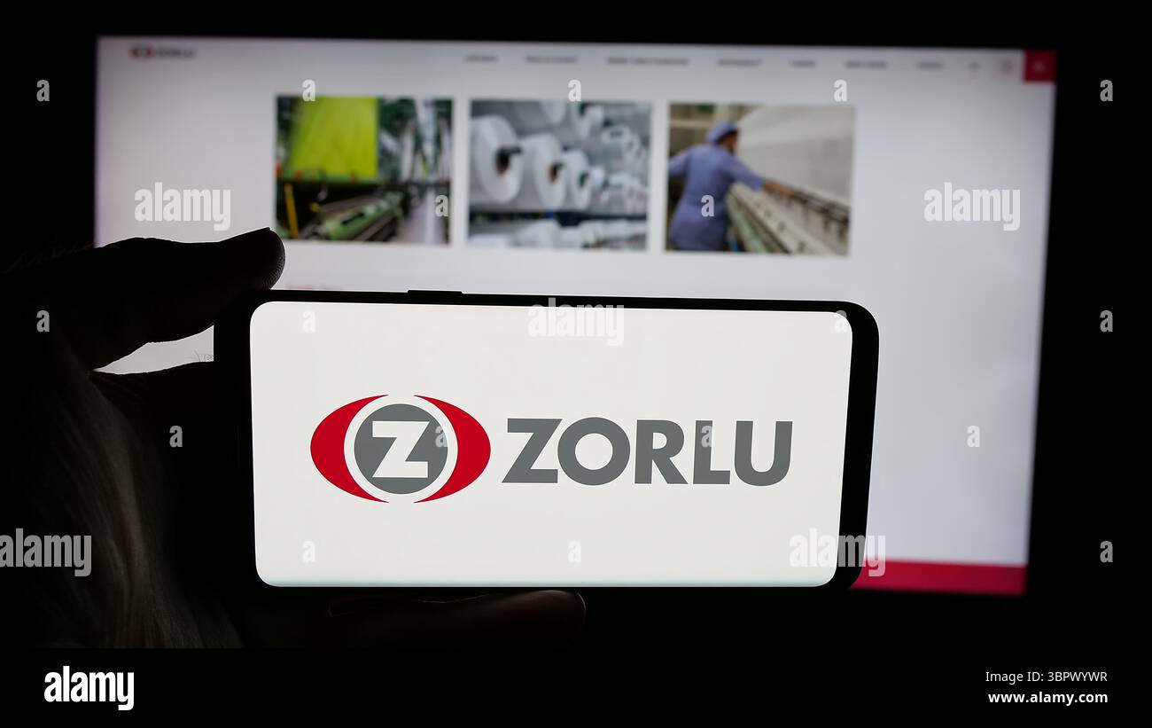 Stoccarda, Germania - 05-07-2025: Persona che detiene un cellulare con il logo della società turca Zorlu Holding A.S., sullo schermo di fronte alla pagina web. Foto Stock
