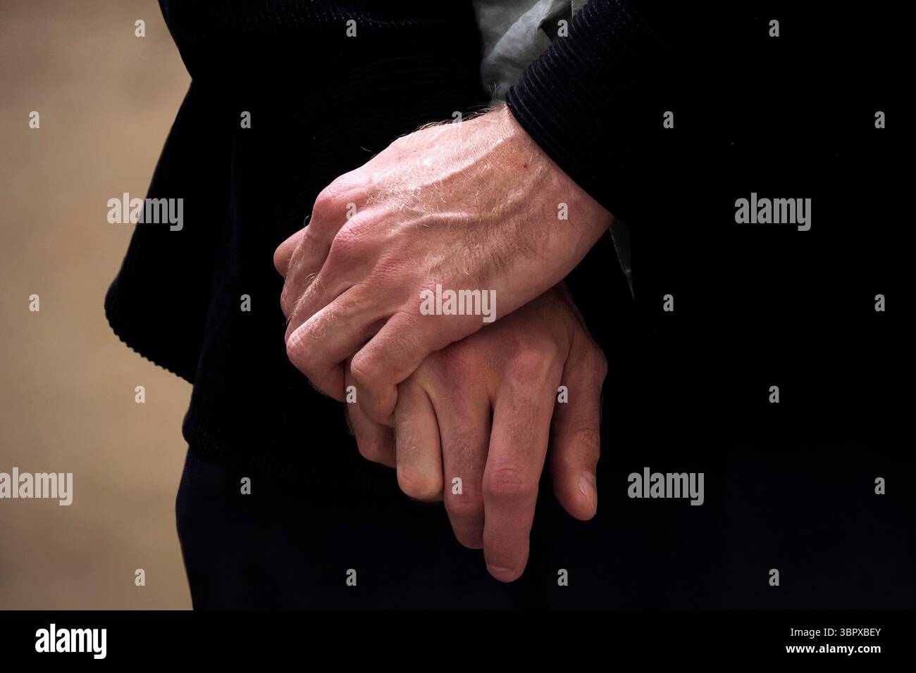 Un uomo ha incrociato i dettagli delle mani, vestito nero Foto Stock