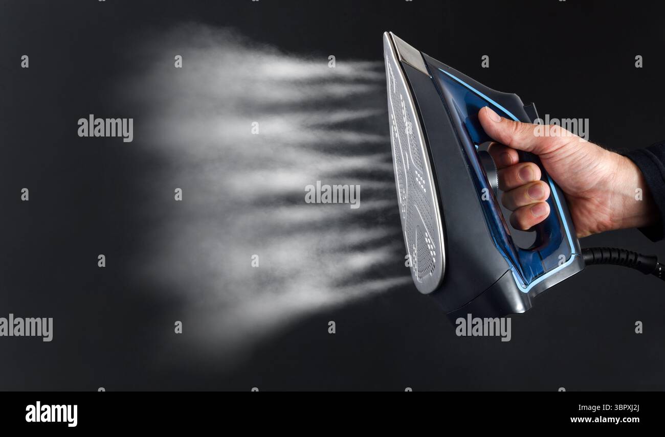 Azionare manualmente il sistema di vapore di un ferro e vedere i getti di vapore su sfondo scuro e isolato Foto Stock