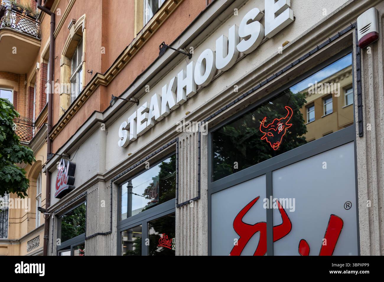Poznan, Polonia - 18 giugno 2025: Facciata del ristorante Evil Steakhouse con il suo esclusivo cartello rosso toro al neon e il grande logo del marchio Foto Stock