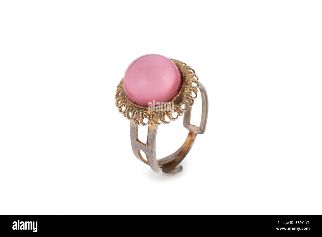 Vecchio e usurato anello di bronzo da donna, con pietra rosa, isolato su sfondo bianco con bokeh Foto Stock
