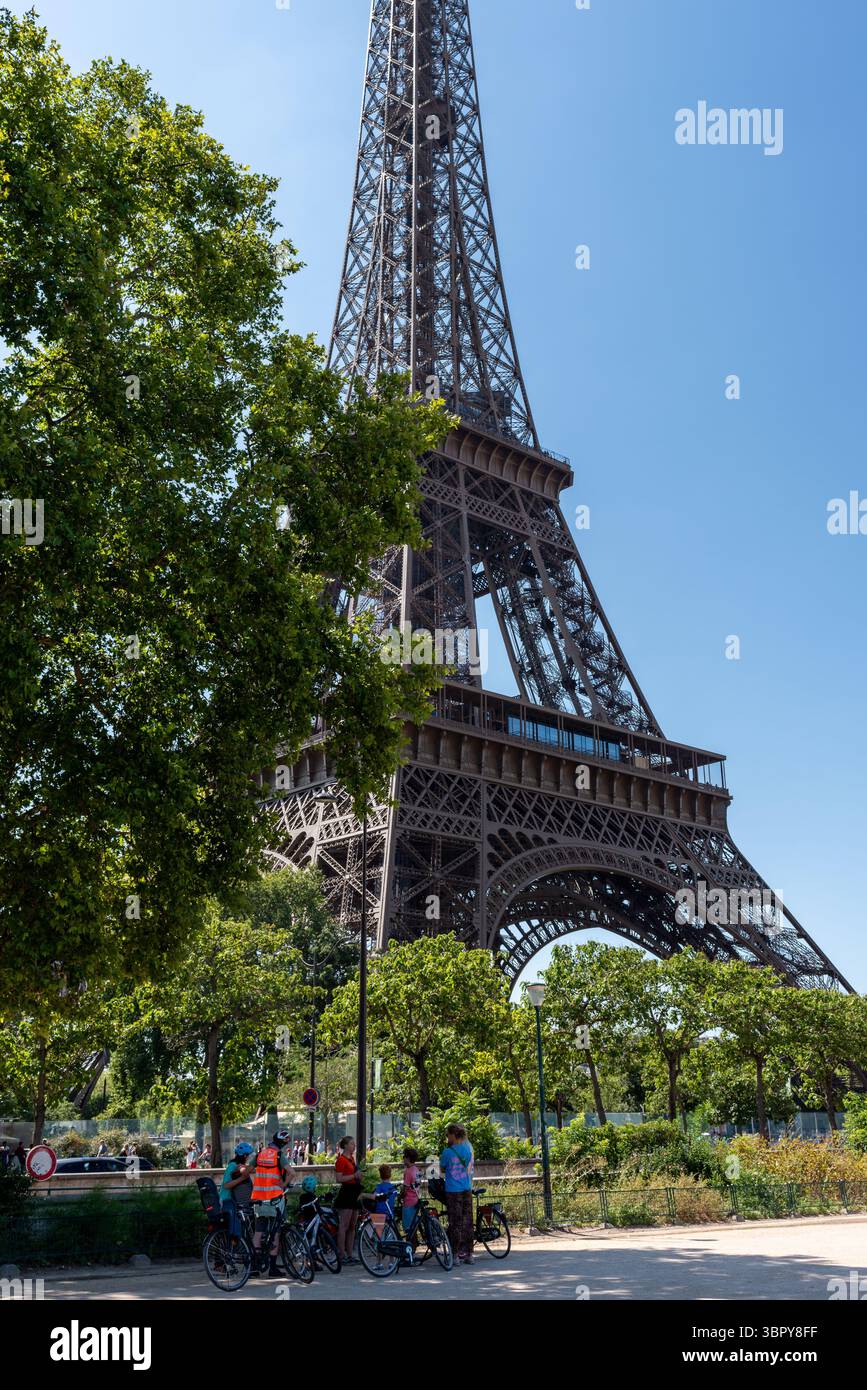 Guida turistica con un gruppo di turisti in bicicletta di fronte alla Torre Eiffel in una giornata estiva di sole. Visita turistica di Parigi in bicicletta Foto Stock