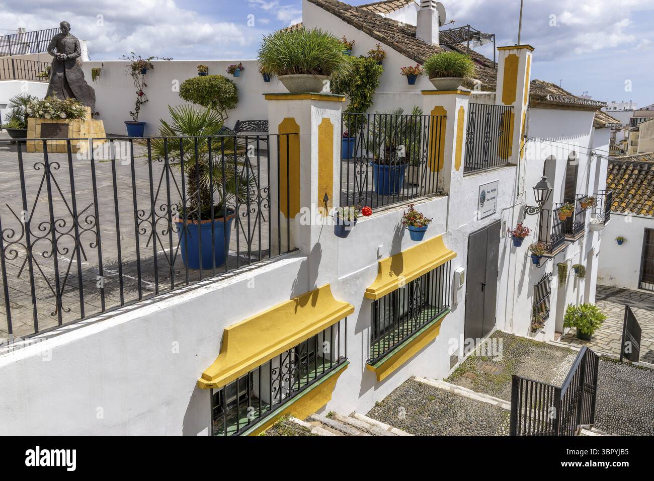 Scala con molti tessuti floreali su giallo e bianco lungo il muro, fino a Plaza San Francisco con scultura in bronzo del sacerdote Estatua padre Foto Stock