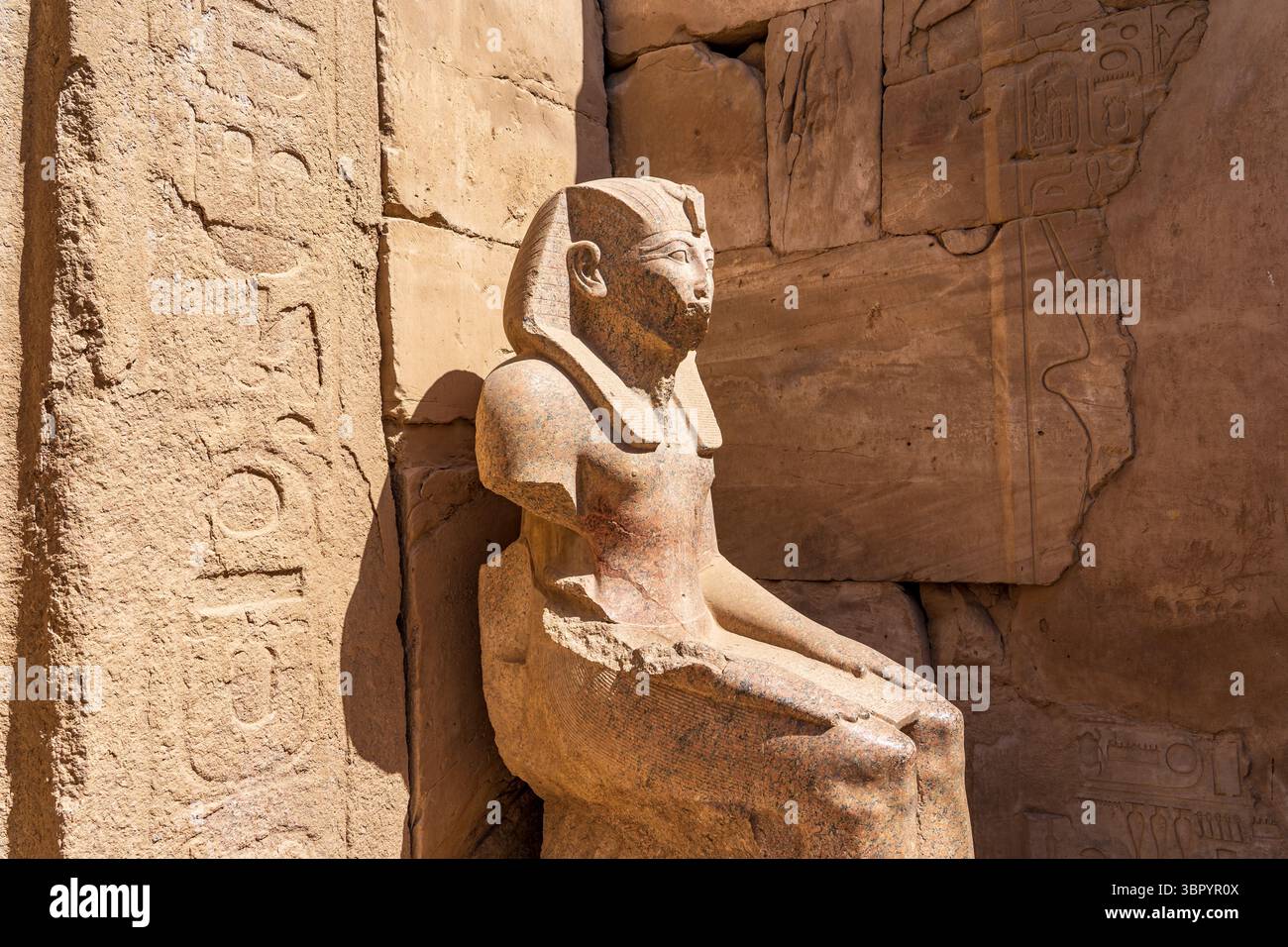 Statua seduta della regina Nefertari, situata ai piedi di uno dei colossi di Ramsete II nel cortile di Ramsete II del Tempio di Luxor. Foto Stock