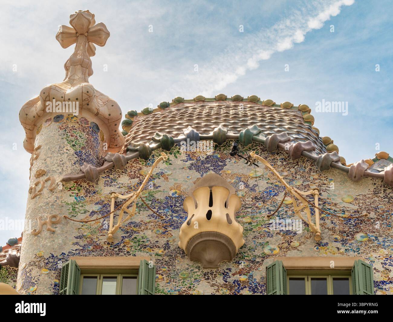L'iconico tetto "dorso del Drago" di Casa Batlló, caratterizzato da piastrelle in ceramica colorata "scale" e una croce, disegnata da Gaudí, Barcellona, Spagna. Foto Stock