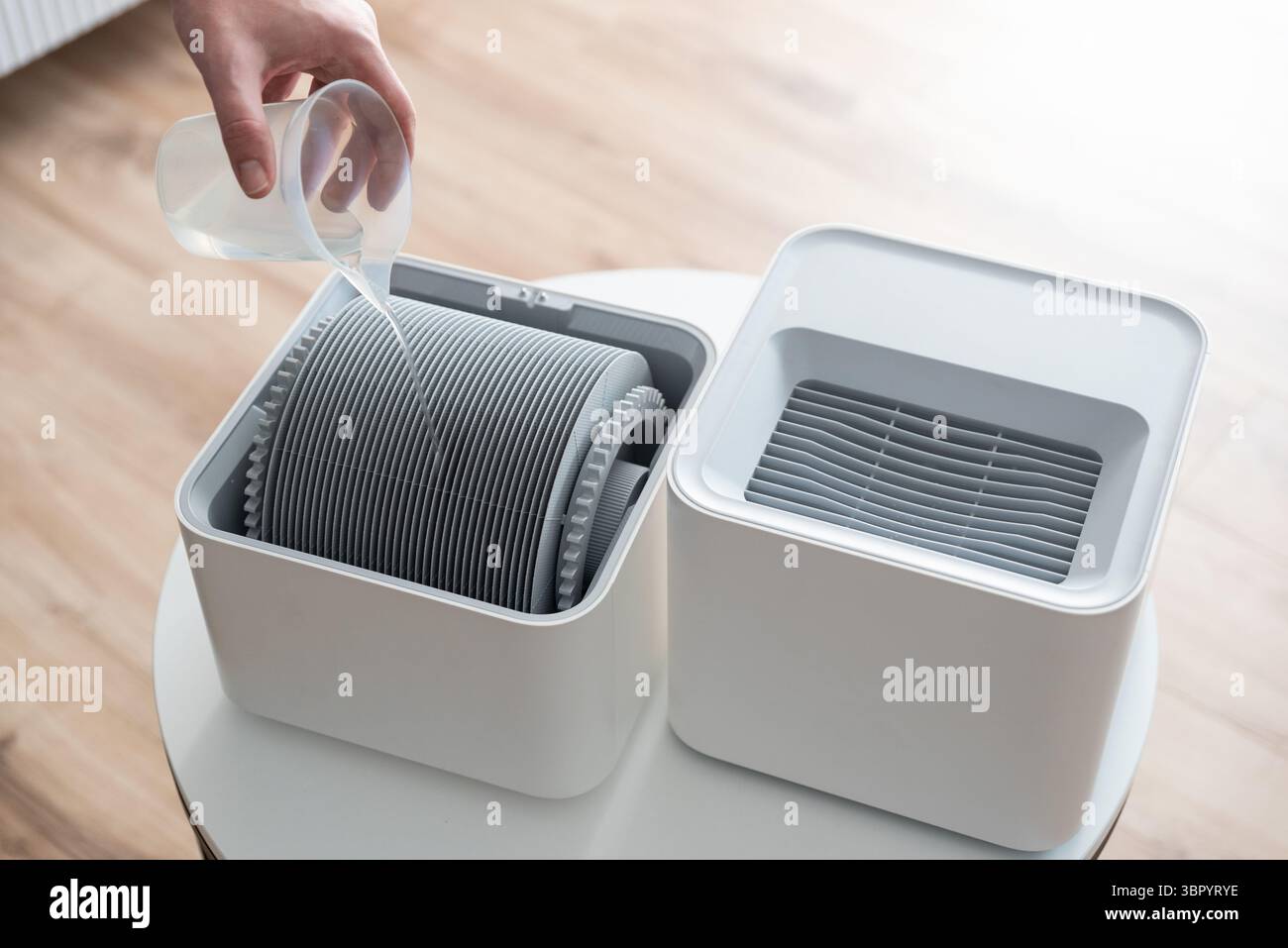 Moderno umidificatore d'aria nel soggiorno. Condizioni di vita confortevoli. Uomo che cambia filtro Foto Stock