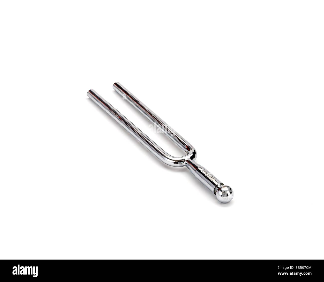 Un diapason in metallo lucido si trova su sfondo bianco, riflettendo la luce sulla superficie lucida. il design semplice ma elegante della forcella è evidente, vetrina Foto Stock