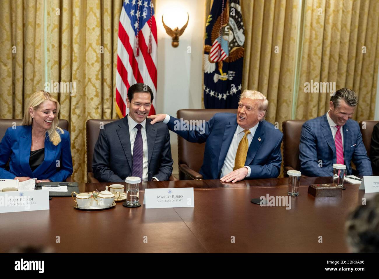 Il presidente Donald J. Trump condivide un momento spensierato con il Segretario di Stato Marco Rubio durante una riunione del Gabinetto, cui si aggiungono il procuratore generale Pam Bondi e altri funzionari. Il gruppo è seduto a un grande tavolo da conferenza in un ambiente formale con bandiere statunitensi e decorazioni presidenziali sullo sfondo. Ripresa alla Casa Bianca, Washington, D.C., l'8 luglio 2025. Per gentile concessione della Casa Bianca. Foto Stock