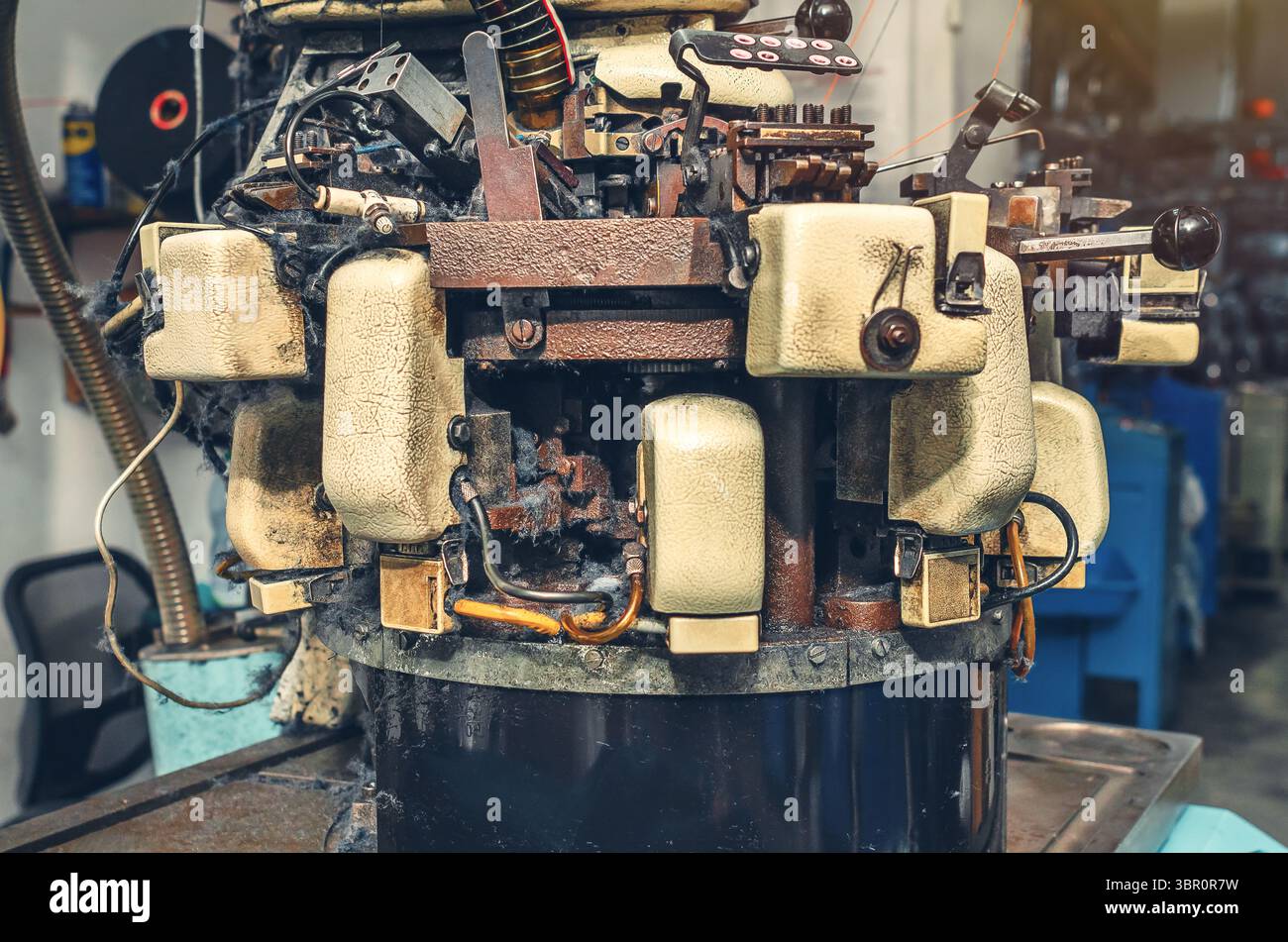 Vista laterale della macchina per maglieria con filato di cotone nella fabbrica di calzini. Macchina per maglieria con polvere di filati. Background industriale Foto Stock