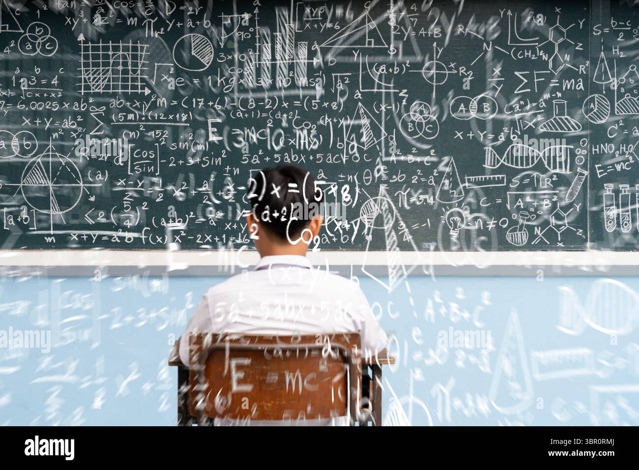 Vista posteriore dello studente seduto alla scrivania che guarda una lavagna piena di formule matematiche e scientifiche, grafici e simboli. Concetto di apprendimento, conoscenza, edu Foto Stock