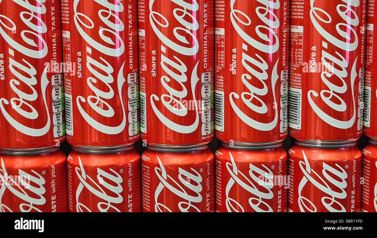 Lattine Coca-Cola impilate in esposizione nel negozio.riga.Lettonia.10.07.2025 - Immagine stock catturata con smartphone