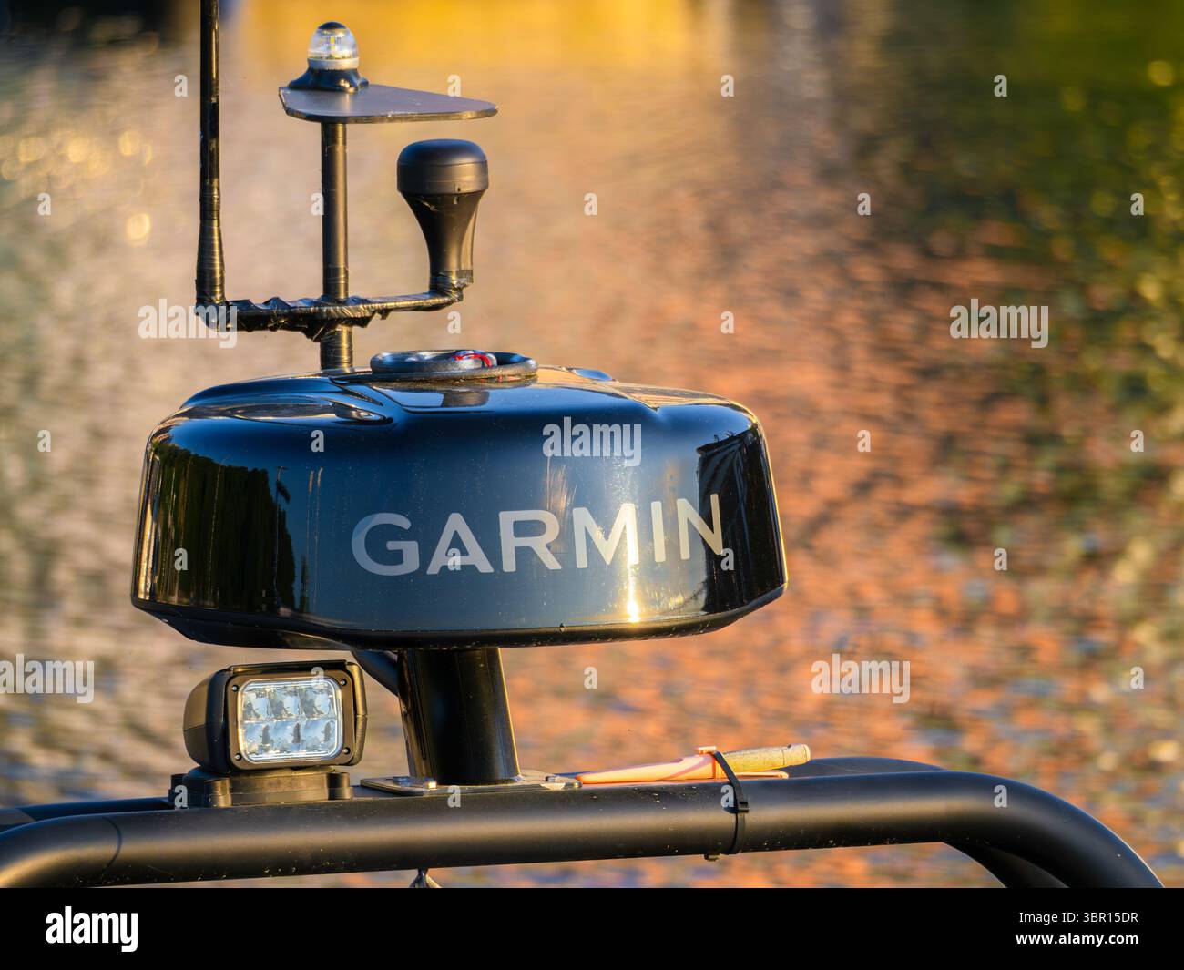 Stoccolma, Svezia - 3 giugno 2025: Primo piano di un sistema radar marino Garmin montato su una barca, con uno sfondo d'acqua sfocato che riflette il sole dorato Foto Stock