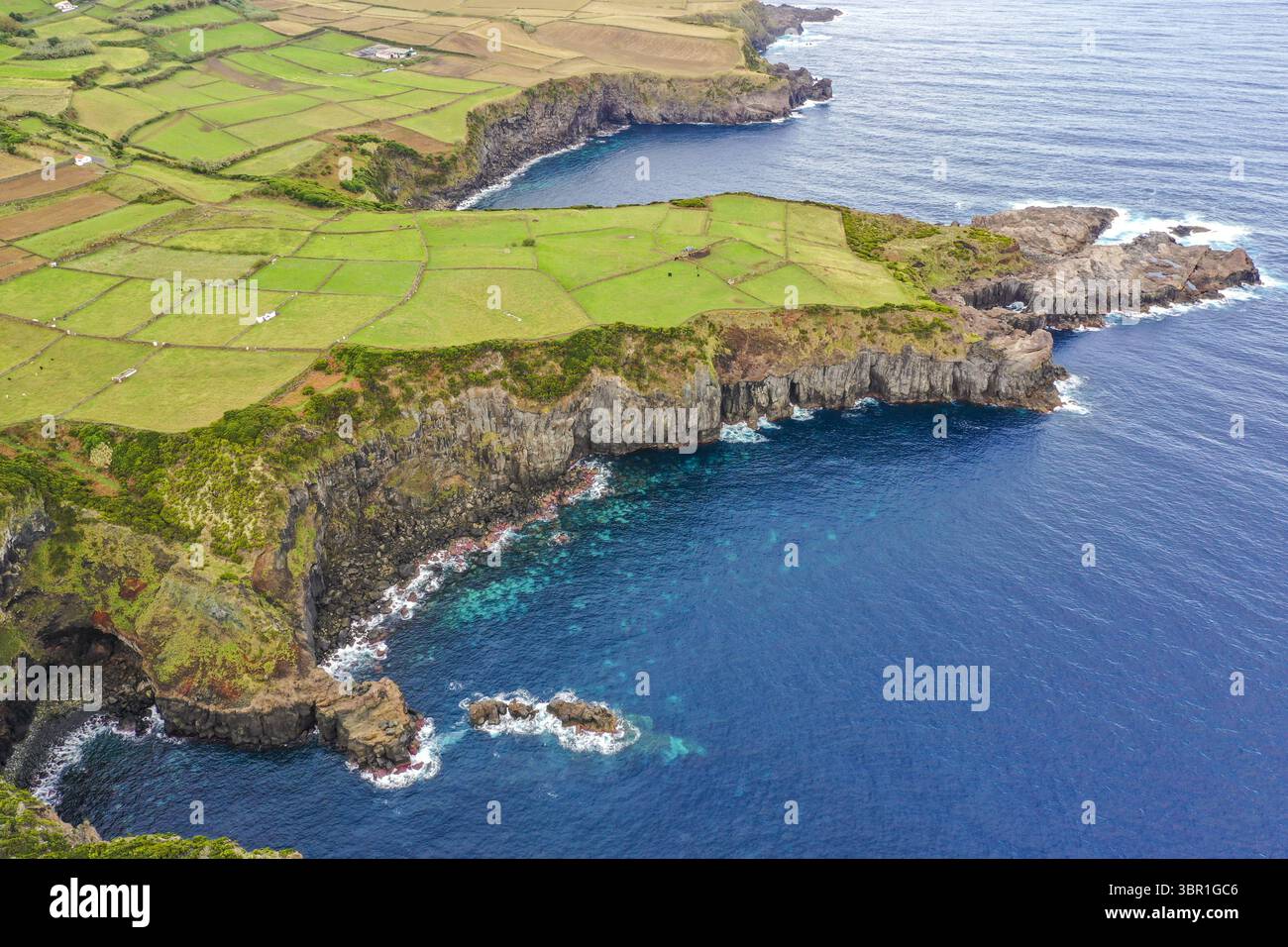 Vista aerea della costa frastagliata in contrasto con i vivaci pascoli verdi dell'isola di Terceira, di Agualva, delle Azzorre e del Portogallo. Foto Stock
