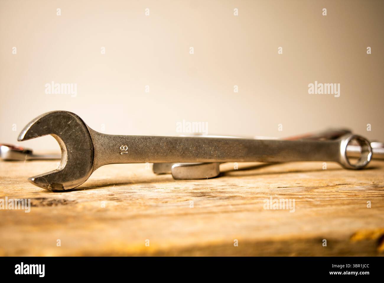 Una chiave combinata in acciaio da 18 mm ben visibile su una superficie in legno testurizzato, che incarna temi di riparazione, fai da te e cura artigianale. Foto Stock