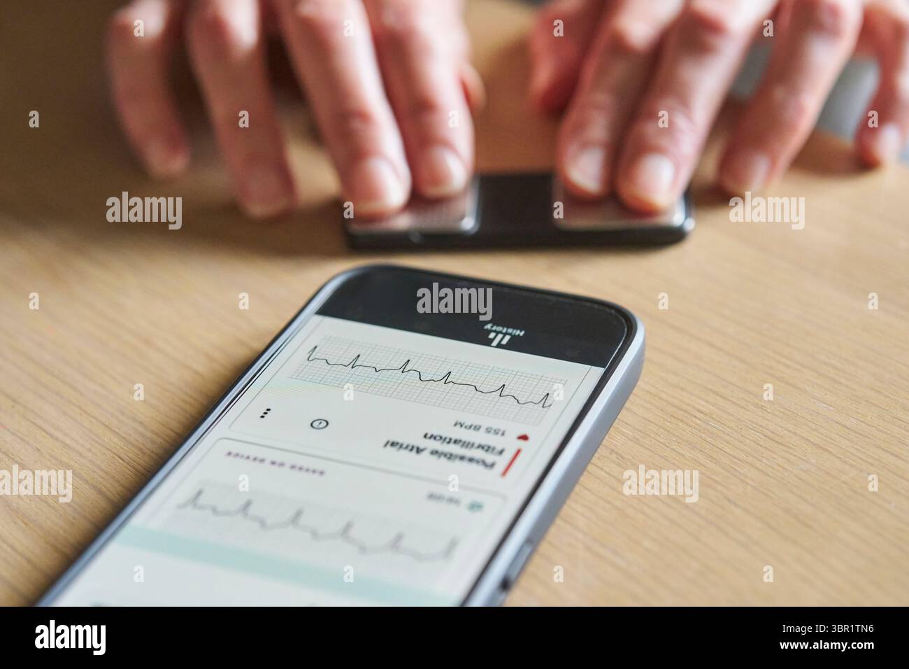 Primo piano di una donna che utilizza un monitor wireless e un'app sul telefono per controllare la frequenza cardiaca Foto Stock