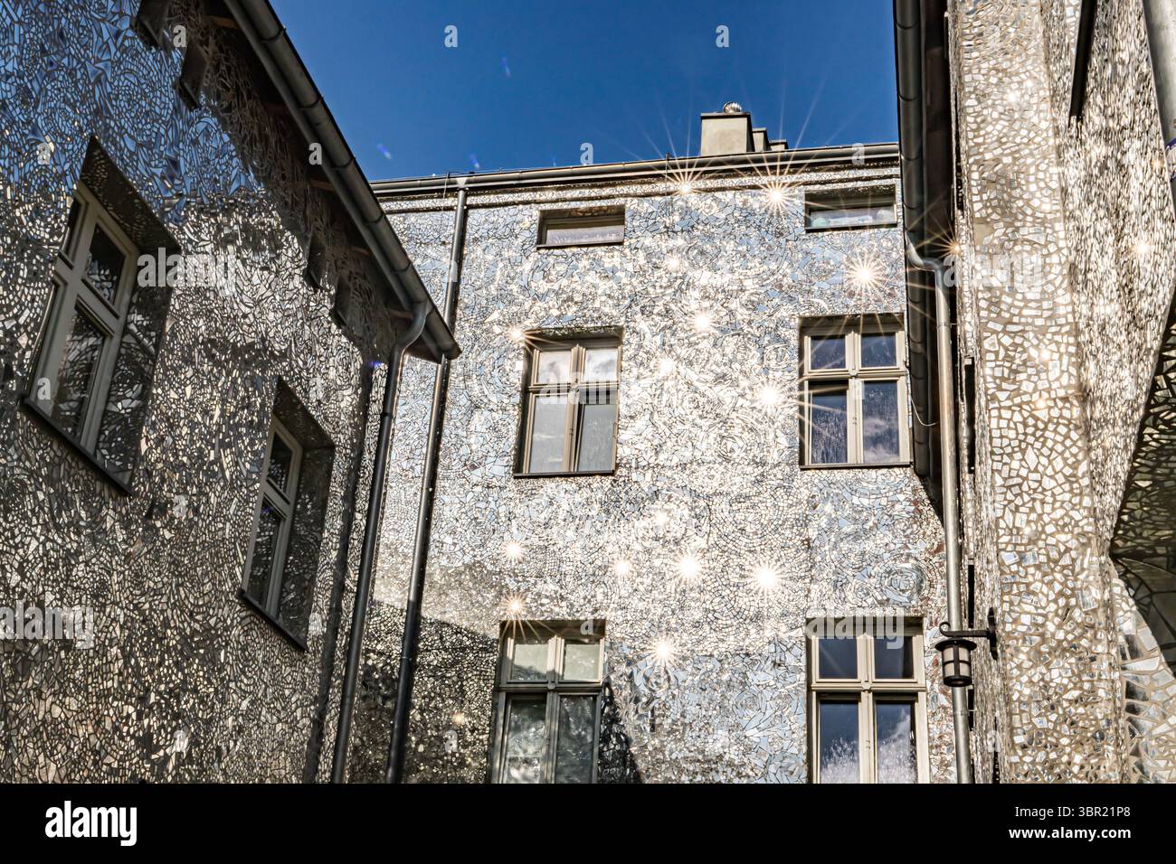 Łódź, Polonia. Un cortile coperto da piastrelle a mosaico a specchio che riflettono la luce del sole e creano effetti artistici di luce sulle pareti. Foto Stock