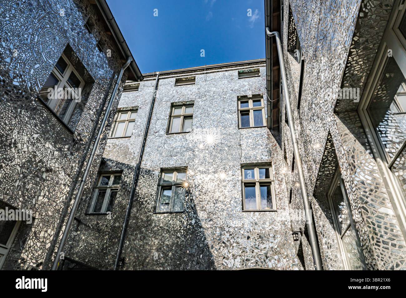 Łódź, Polonia. Un cortile coperto da piastrelle a mosaico a specchio che riflettono la luce del sole e creano effetti artistici di luce sulle pareti. Foto Stock
