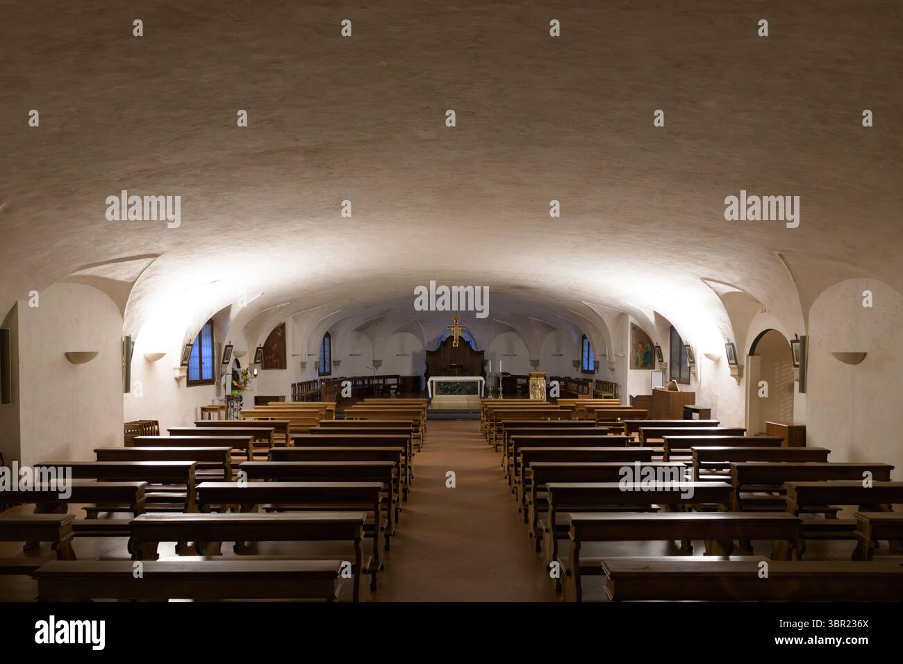 Cripta della Basilica di Santa Giustina, Padova, Italia. Interni con panchine in legno e illuminazione soffusa che creano un'atmosfera solenne. Foto Stock