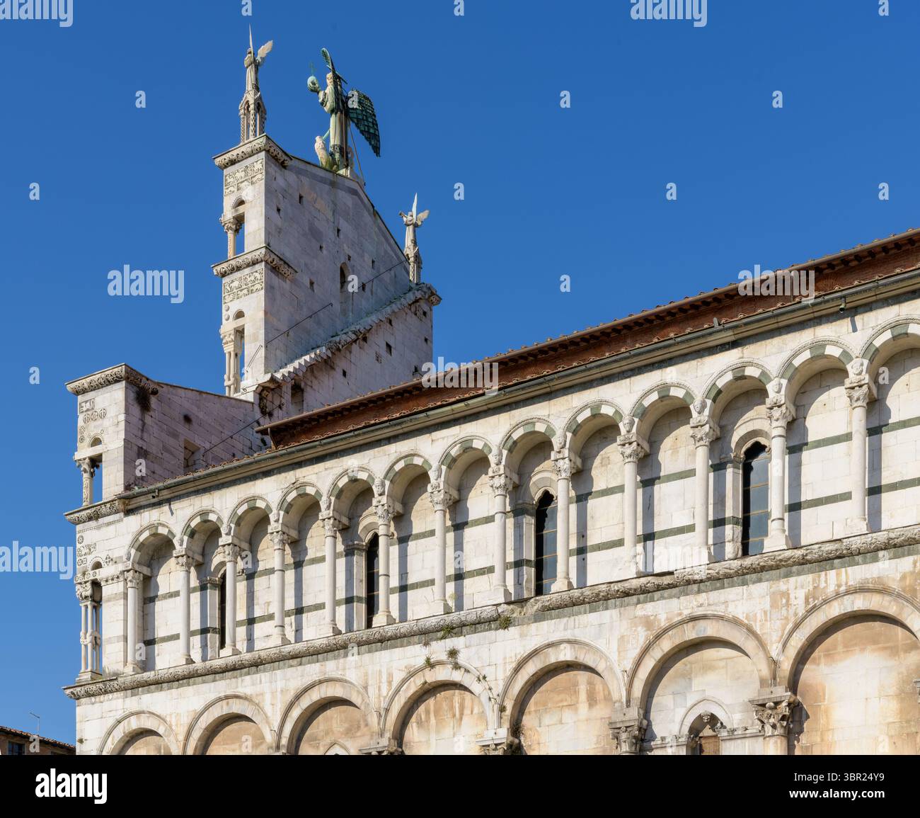 Archi ciechi e finestre del clericembalo di San Michele in foro, Lucca, Italia, con strisce marmoree alternate e portici decorativi in stile romanico. Foto Stock