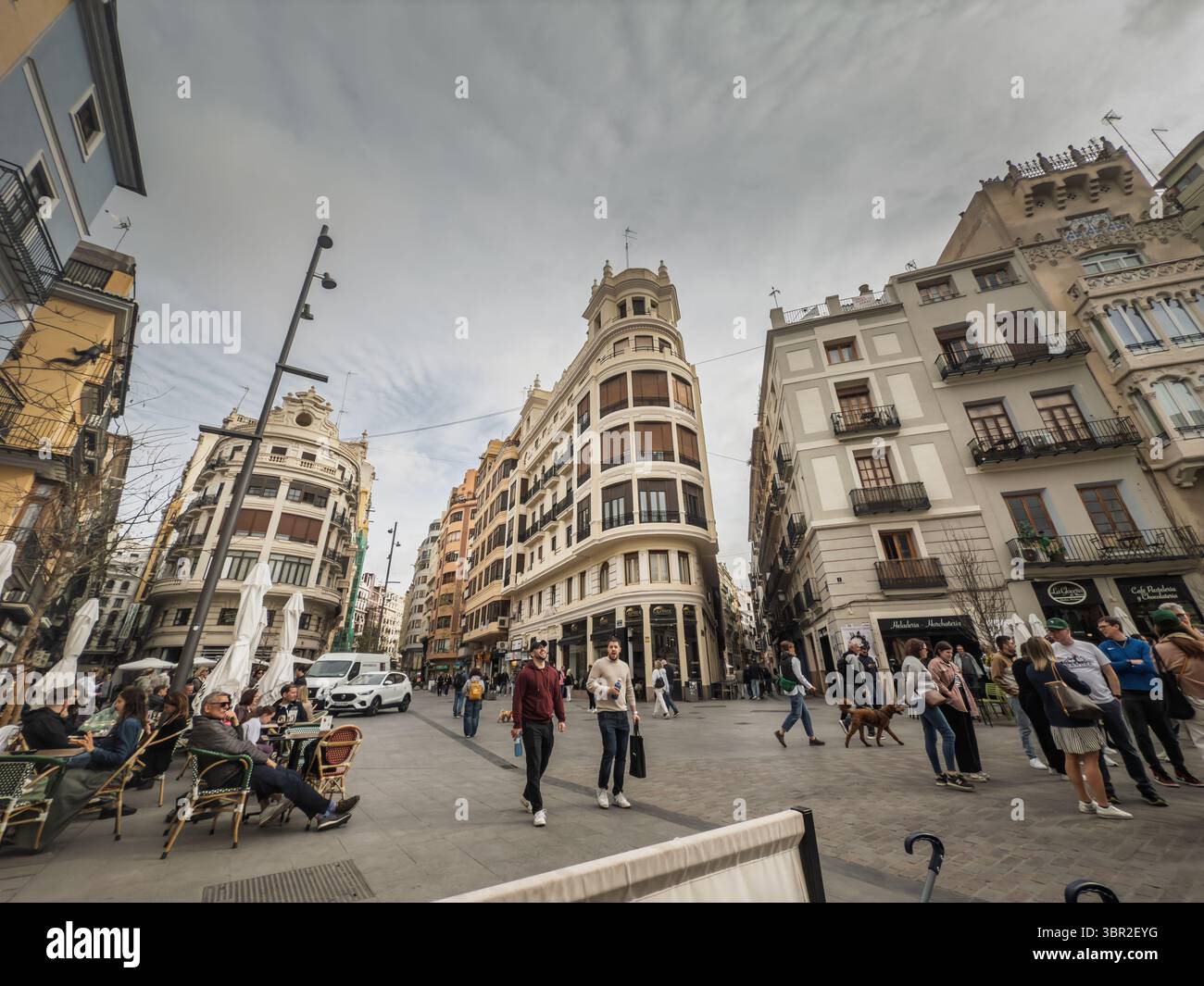 VALENCIA, SPAGNA - 15 APRILE 2025: Vita quotidiana a Valencia Placa del Mercat, mentre la gente del posto e i turisti passeggiano tra le vecchie facciate, rilassati in caffetterie e pas all'aperto Foto Stock