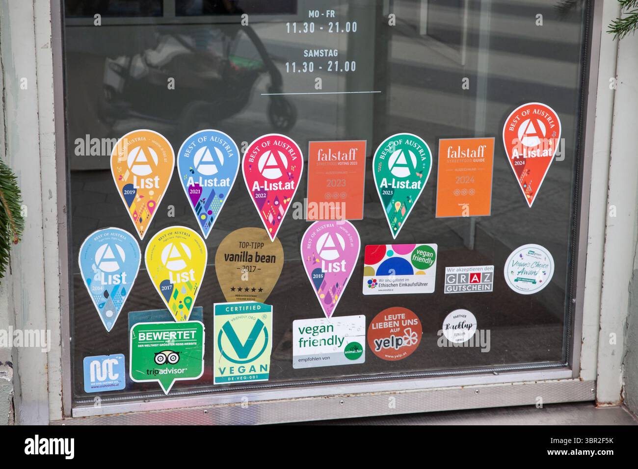 GRAZ, AUSTRIA - 17 DICEMBRE 2024: Porta a Graz con Una lista di spille Best of Austria, cartelli Falstaff e loghi vegani amichevoli mostrano come i ristoranti fla Foto Stock