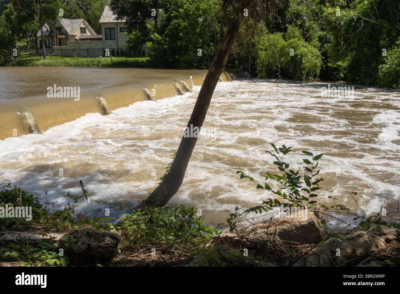 Texas 2025 acque fangose rilasciate dalla diga di controllo delle inondazioni a monte scorre sopra una piccola diga Foto Stock