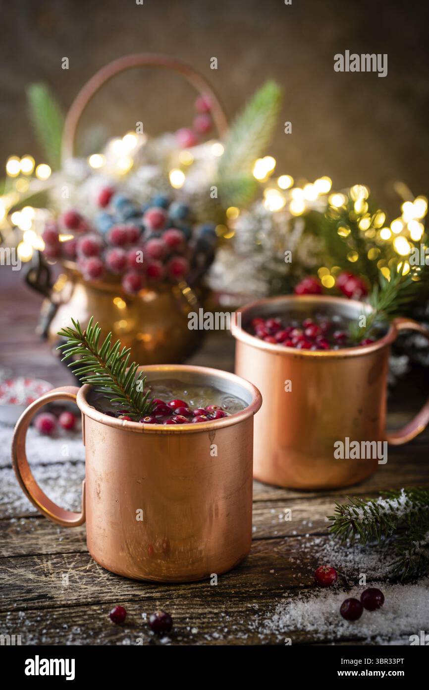 VIN brulé con mirtillo rosso in tazza di rame con decorazioni natalizie su tavolo di legno Foto Stock