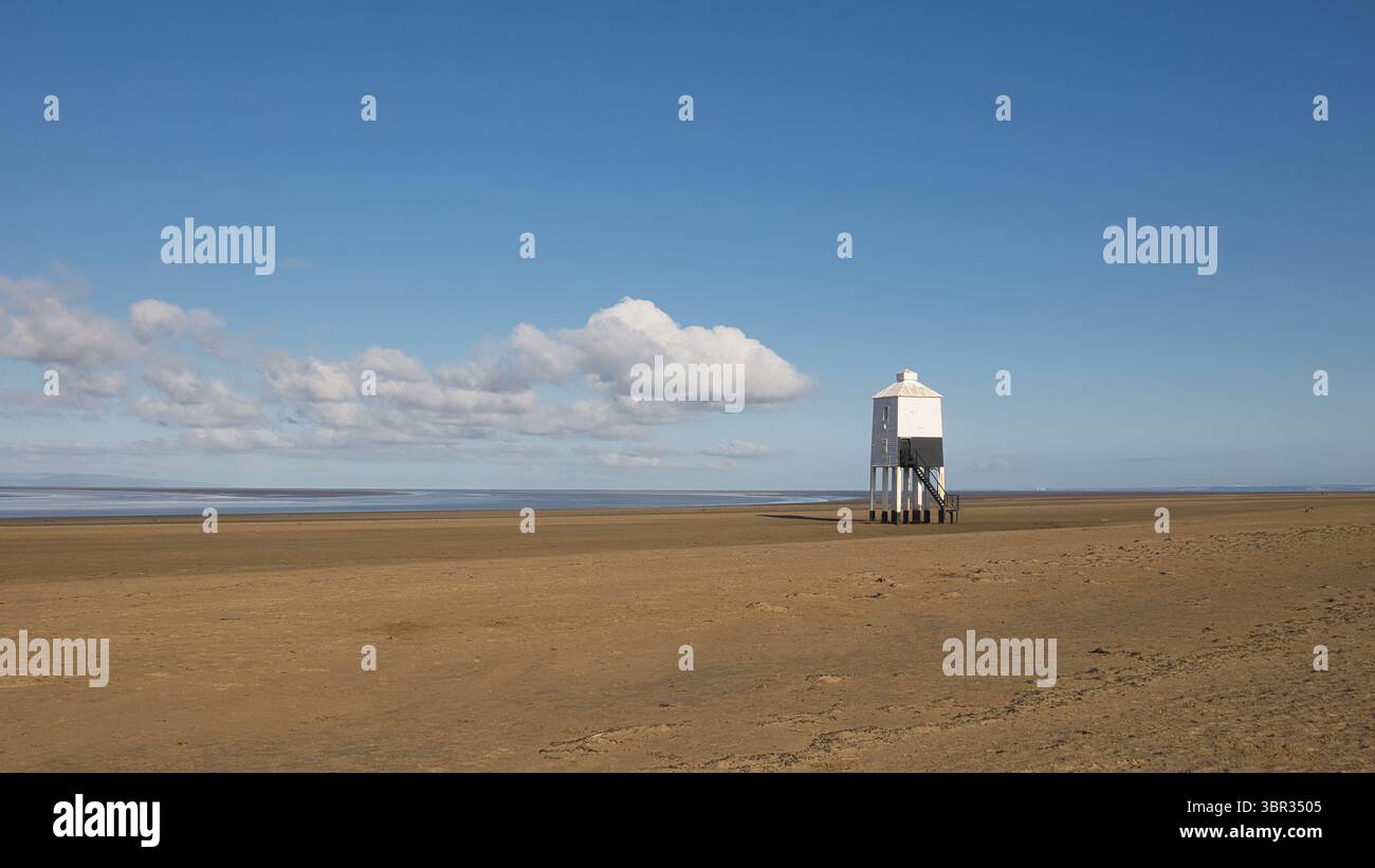 Una vista panoramica del faro basso di Burnham on Sea. Non ci sono persone sulla spiaggia sabbiosa e viene portata contro un cielo blu con il sole estivo Foto Stock