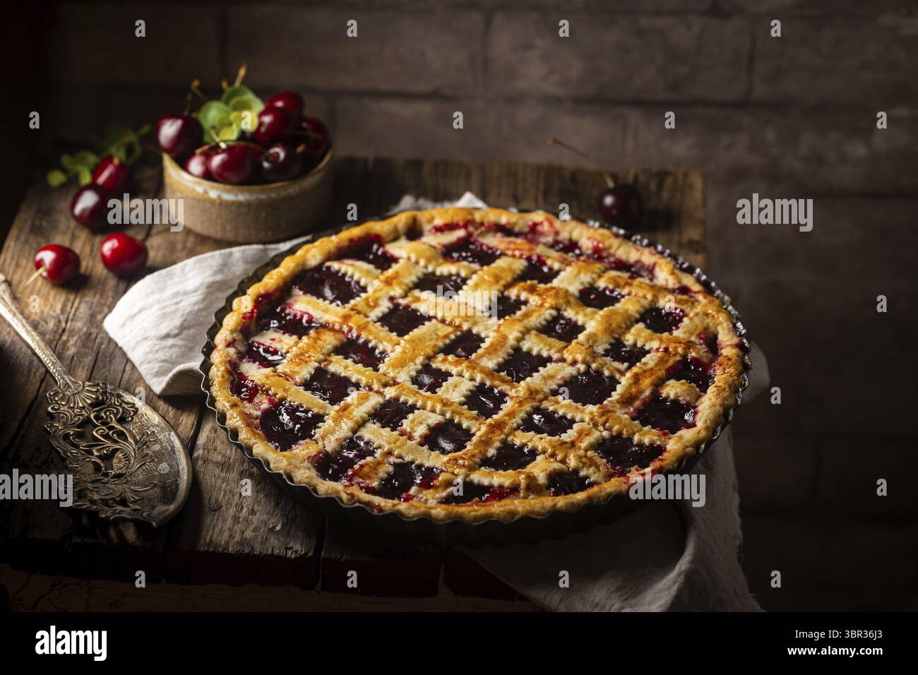 Deliziosa torta di ciliegie classica fatta in casa con una crosta traballante su sfondo rustico scuro Foto Stock
