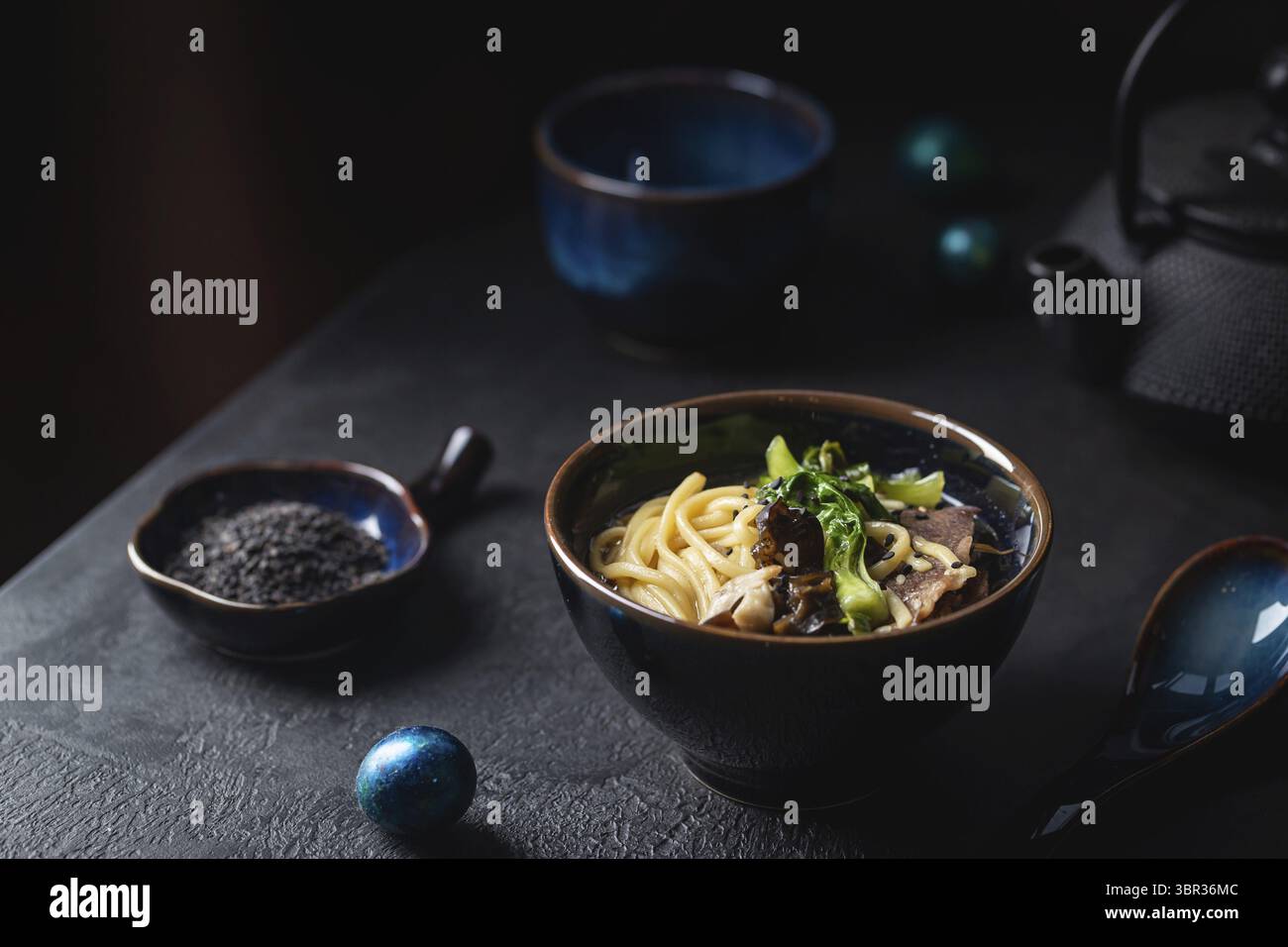 Asian spaghetti ramen zuppa con carne di manzo, funghi Oyster e verdure in vaso su sfondo scuro Foto Stock