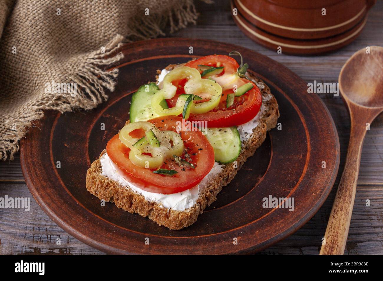 Sandwich con formaggio, pomodoro, cetriolo e pepe su un piatto di argilla marrone Foto Stock