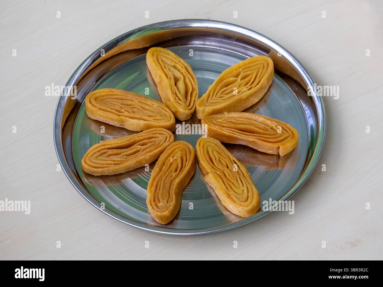 Delizioso dolce Gaja, a forma di fiore su piatto di acciaio, fondo in legno. Conosciuto come Khaja o Chirote, questo dolce tradizionale è un festi bengalese e indiano Foto Stock