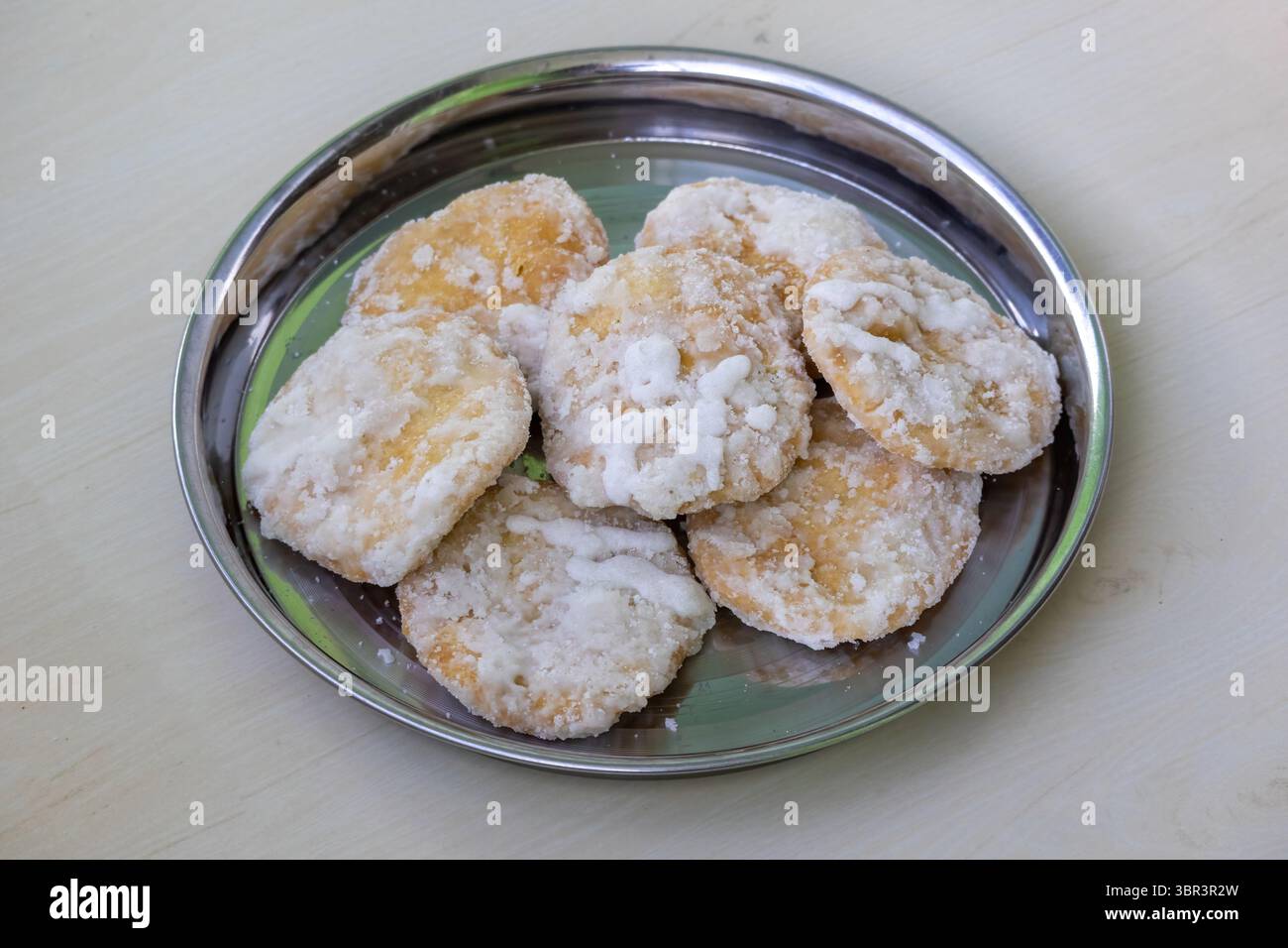 Gustoso dolce Khaja su un piatto di acciaio con fondo in legno. Questa pasticceria fritta immersa nello sciroppo di zucchero, nota anche come Gaja o Chiroti, è una popolare t Foto Stock