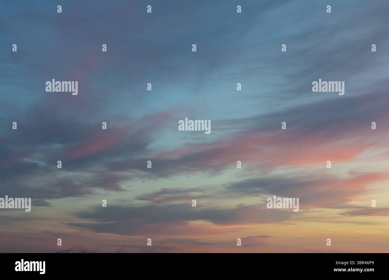 I vibranti colori crepuscolari si fondono nel cielo sopra un tranquillo paesaggio durante il tramonto mostrando morbide nuvole e un'atmosfera tranquilla che ispira calma. Foto Stock