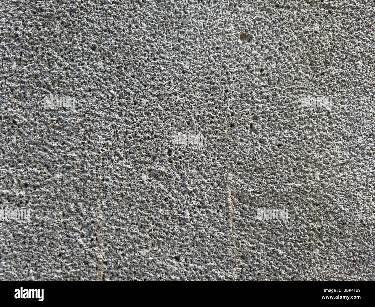 Parete di cemento poroso con fori, sfondo della parete. Ci sono dei piccoli buchi nel muro Foto Stock